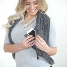 Blonde lady with blue sweater and infinity scarf showing how functional scarves with pockets are used to store personal items while on vacation.