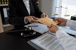 Image of two people sitting at a desk exchanging a manila envelope of papers containing a Constitutional trust contract for the best trust to avoid probate entirely
