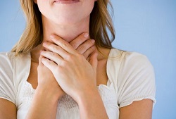 Image of woman holding her throat and learning of the best natural remedies for acid reflux